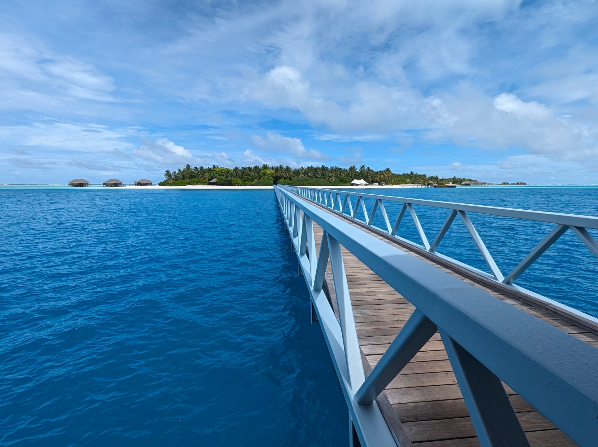 Jetty over a Maldivian lagoon toward a tropical island